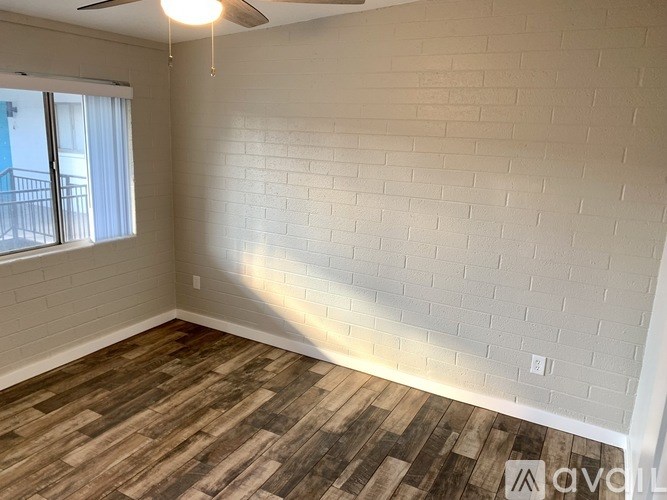 A room with a wooden floor and a white brick wall.