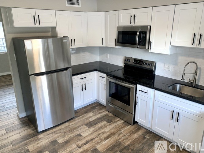 A kitchen with a stainless steel refrigerator, microwave, oven, and cabinets.