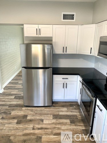 A kitchen with a stainless steel refrigerator and black countertops.