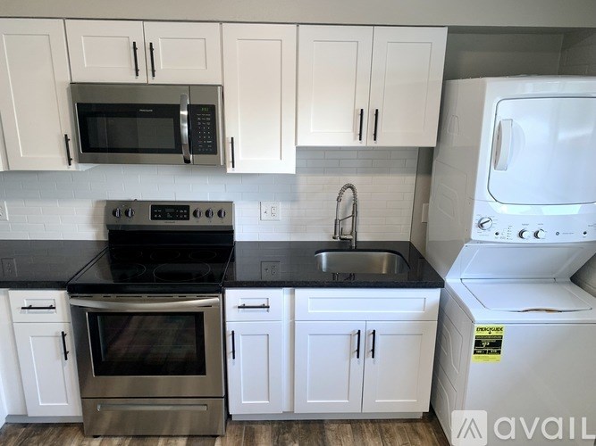 A kitchen with white cabinets and black countertops.