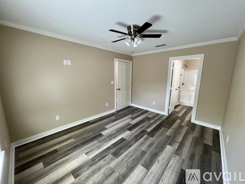 A room with a ceiling fan and wooden flooring.