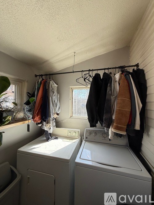 A laundry room with a washer and dryer and clothes hanging up.