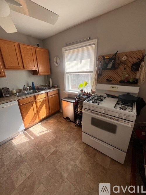 A kitchen with a white stove top oven and a fan on the ceiling.