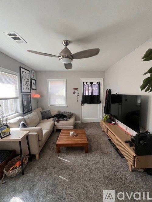 A living room with a television, couch, and a ceiling fan.