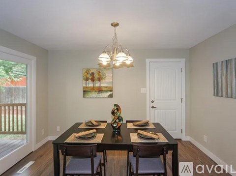 A dining room with a table set for two and a chandelier hanging from the ceiling.
