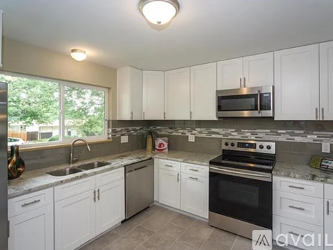 A kitchen with white cabinets and a black stove top oven.