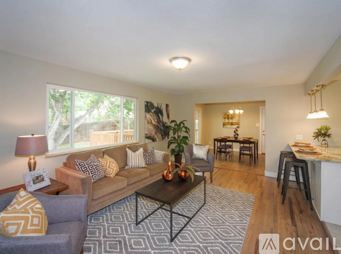 A living room with a grey couch, a coffee table, and a dining table with chairs.