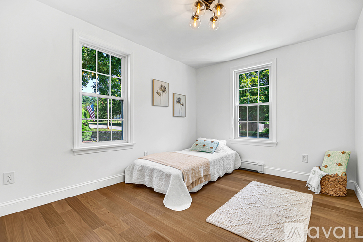 A bedroom with a bed, a chair, and a window.