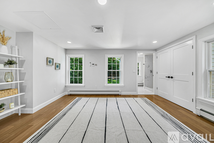 A spacious room with white walls and a striped rug on the floor.