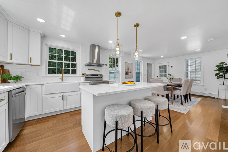 A kitchen with white cabinets and a large island with bar stools.
