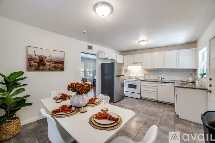 A dining room with a white table set for a meal.