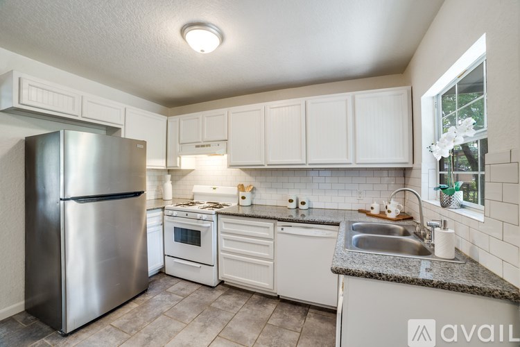 A kitchen with white cabinets and a stainless steel refrigerator.