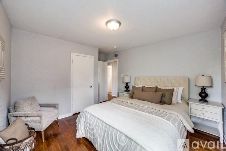 A bedroom with a large bed, a chair, and two lamps.