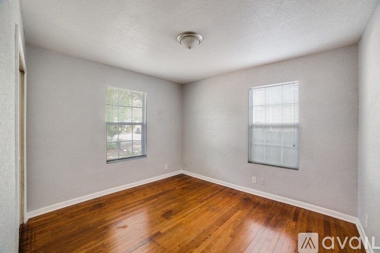 A room with wooden floors and two windows.