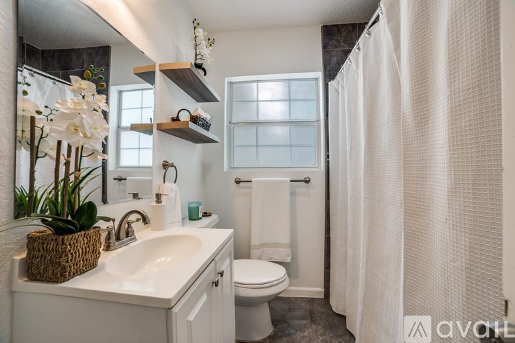 A bathroom with a white sink, toilet, and shower curtain.