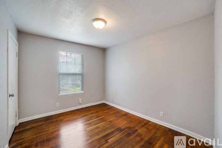 A room with wooden floors and a window with blinds.