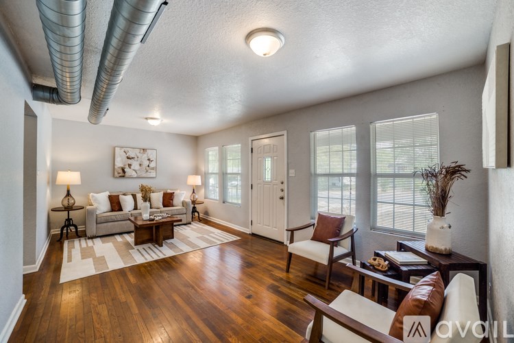A living room with a white couch, a brown armchair, and a wooden floor.