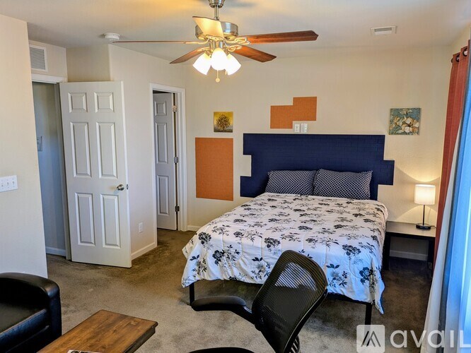 A bedroom with a bed, chair, and a ceiling fan.