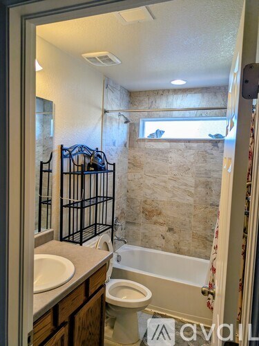 A room with a bed, chair, and a television mounted on the wall.