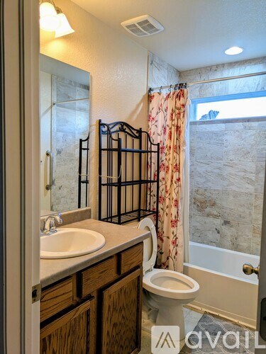 A bathroom with a toilet, sink, and a window with a curtain.
