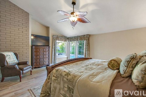 A bedroom with a large bed and a ceiling fan.