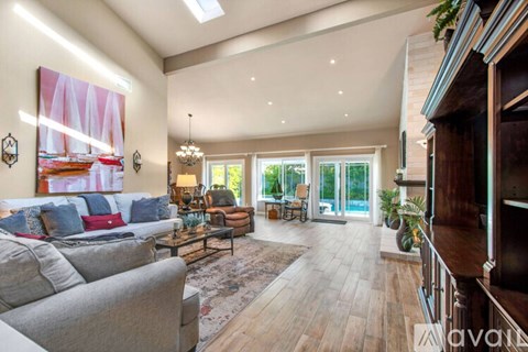 A spacious living room with a grey sofa and a chandelier.