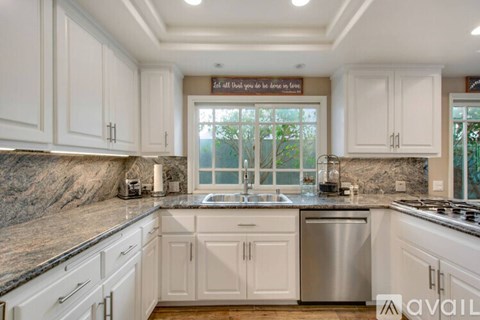 A kitchen with white cabinets and a marble countertop.