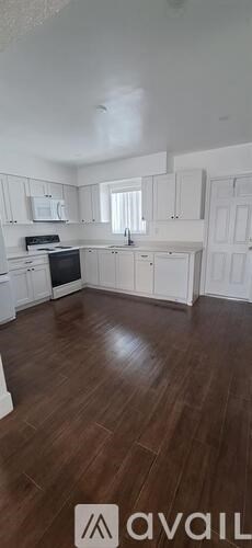 A kitchen with white cabinets and a wooden floor.