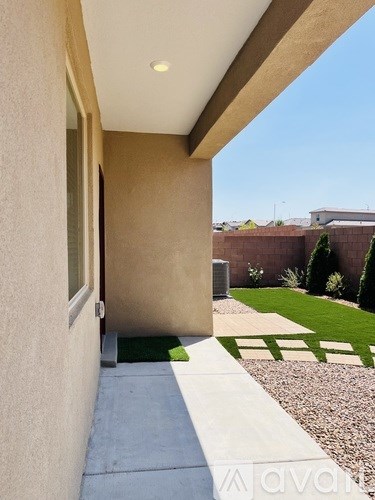 A modern house with a tan exterior and a small garden area.