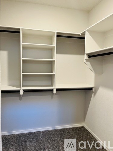 A white shelving unit with multiple shelves is mounted on a wall.