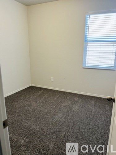 A room with a carpeted floor and a window with blinds.
