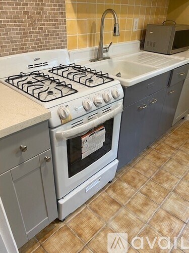 A white gas stove in a kitchen with a microwave on the counter.