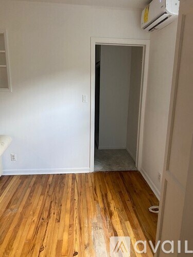 A room with a wooden floor and a door leading to another room.