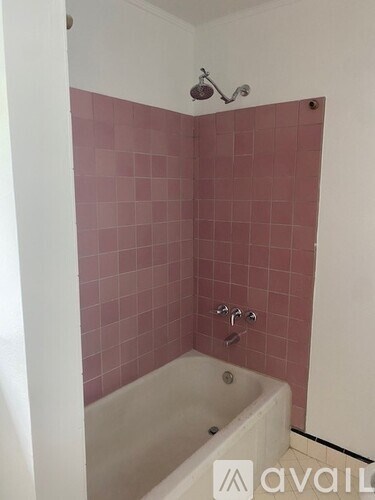 A bathroom with a pink tiled shower area.
