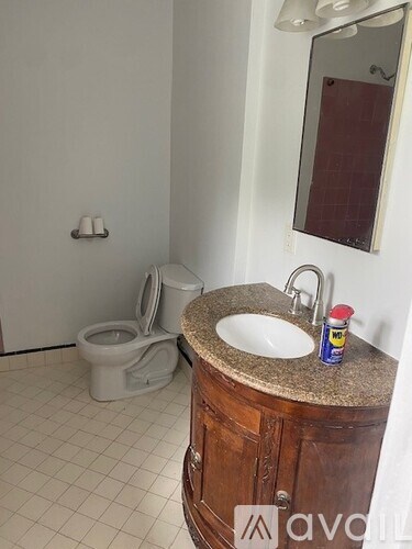 A bathroom with a toilet, sink, and mirror.