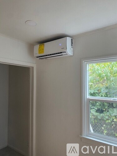A wall-mounted air conditioner unit is installed above a window in a room.