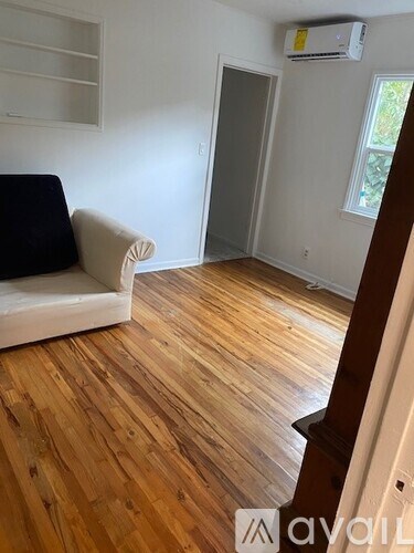 A living room with a white couch and wooden floors.