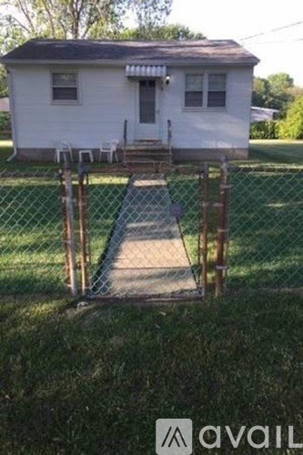 A white house with a brown roof and a fence around it.