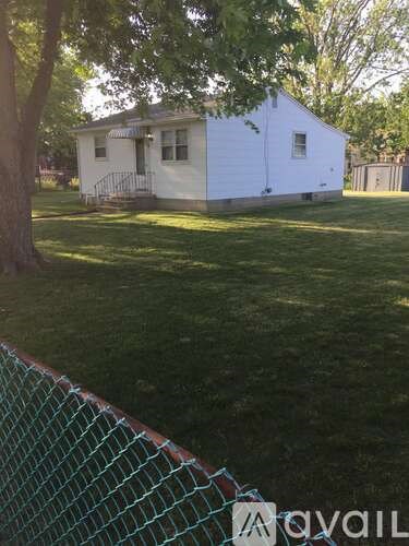 A white house with a green fence in front of it.