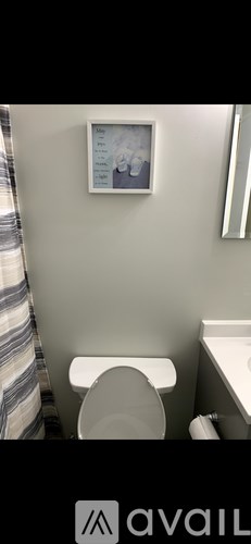 A bathroom with a toilet, sink, and a picture on the wall.