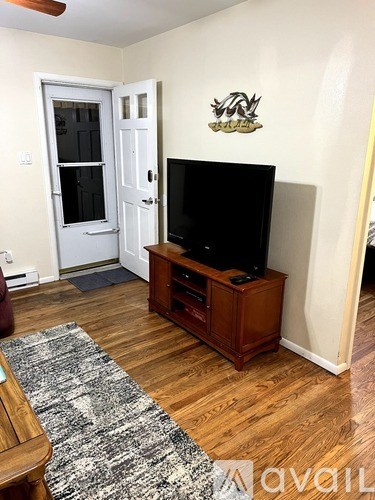 A room with a television on a stand and a rug on the floor.