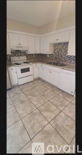A kitchen with white cabinets and a tiled floor.