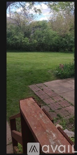 A wooden bench sits in front of a green lawn.