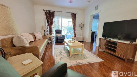 A living room with a couch, a chair, a coffee table, and a television.