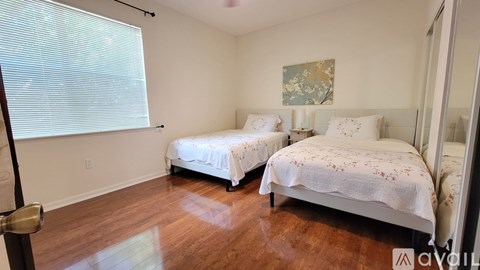 Two beds in a room with wooden floors and white walls.