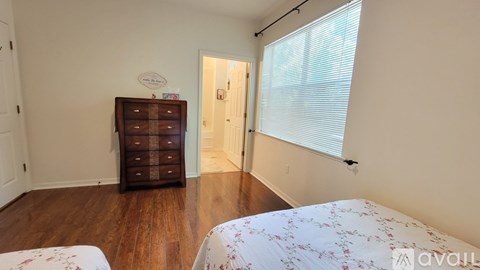 A bedroom with a bed, dresser, and window.