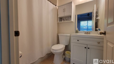 A bathroom with a toilet, sink, and cabinets.