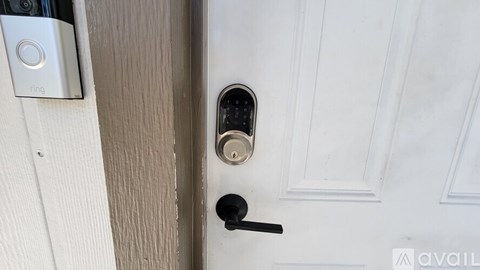 A door with a black handle and a Ring device on the wall.