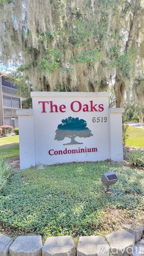 A sign for The Oaks Condominium with a tree graphic on it.