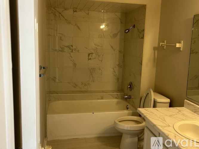 A bathroom with a marble patterned shower and a white toilet.